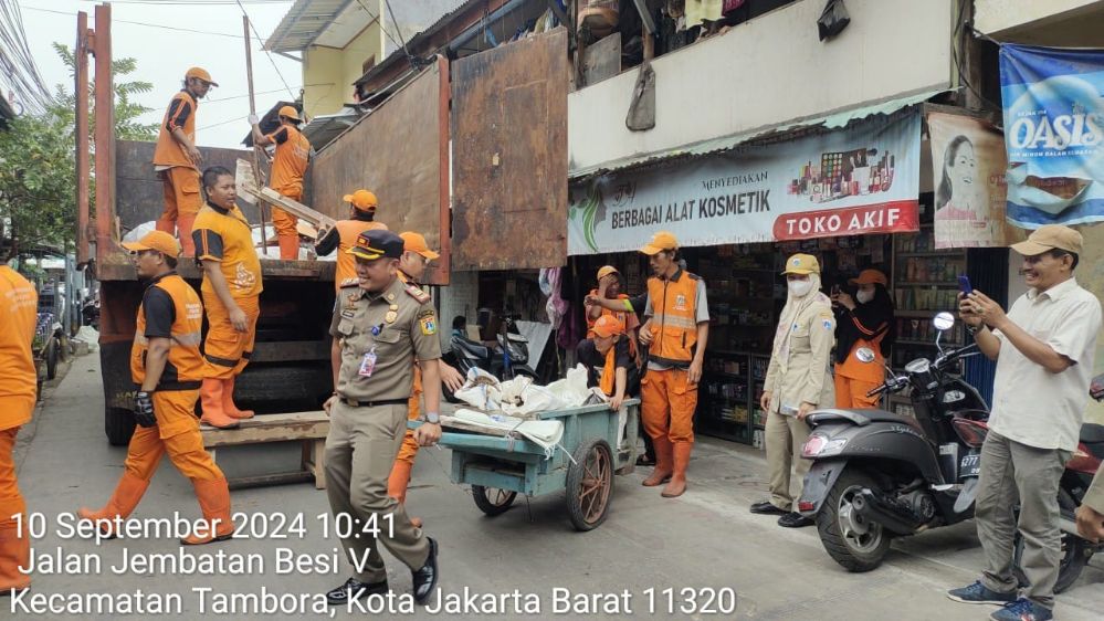 Kasatgas Pol PP Kel Jembatan Besi, Apit AM, SH, MH saat membantu pembersihan sampah rumah warga yang roboh. 