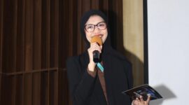 Foto: Asri Pratiwi Tenggara pembawa acara memandu jalannya kegiatan dengan penuh semangat di atas panggung. Dengan mengenakan busana formal, ia tampak percaya diri menyampaikan informasi kepada audiens yang hadir, menciptakan suasana acara yang hangat dan interaktif.