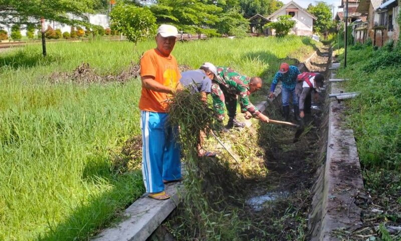 Foto: Babinsa Kelurahan Kampungdalem, Sertu Tugimin bersama warga bergotong royong membersihkan saluran air dari sampah dan rumput liar di Kecamatan Tulungagung, Sabtu (11/10/2025). 