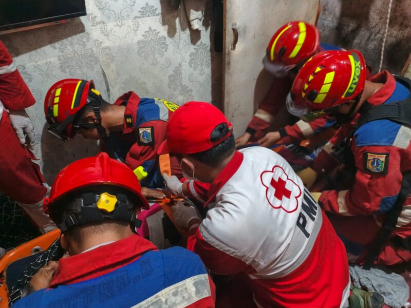 Foto: Petugas Palang Merah Indonesia (PMI) Kota Jakarta Pusat bersama tim Damkar Jakarta Pusat mengevakuasi seorang warga sakit dari lantai dua rumah di kawasan Utan Panjang, Kecamatan Kemayoran.