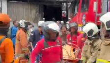 Foto: Petugas pemadam kebakaran mengevakuasi korban dari dalam gedung yang terbakar di kawasan Cempaka Baru, Kemayoran, Jakarta Pusat, Selasa (9/12/2025).