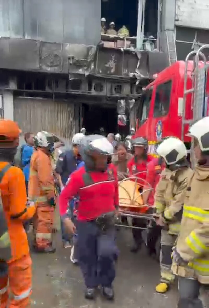 Foto: Petugas pemadam kebakaran mengevakuasi korban dari dalam gedung yang terbakar di kawasan Cempaka Baru, Kemayoran, Jakarta Pusat, Selasa (9/12/2025).
