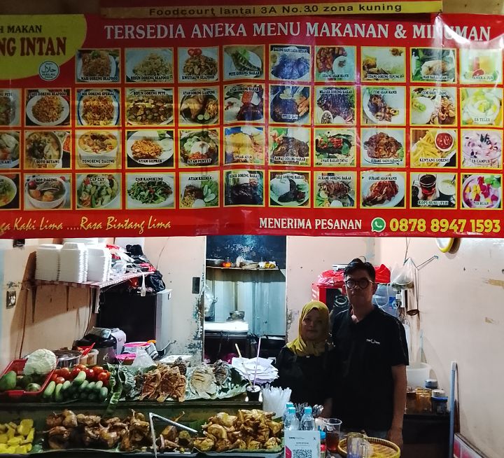 Foto: Idris bersama Istri, pemilik “Saung Intan”, sebuah warung kuliner di lantai 3A nomor 30 zona kuning di Pusat Grosir Cililitan (PGC), Jakarta Timur. (Dok-Okj/FN)