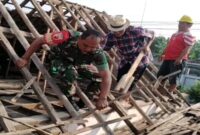 Foto: Seorang Babinsa bersama warga bergotong royong memperbaiki atap rumah milik Djumiati, warga Kelurahan Bendogrit, Kecamatan Sananwetan, Kota Blitar, Minggu (18/1/2026)
