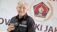 Foto: Dr. Bagus Sudarmanto, S.Sos., M.Si. Seorang pengurus Persatuan Wartawan Indonesia (PWI) DKI Jakarta berpose di sela kegiatan organisasi, dengan latar belakang logo PWI