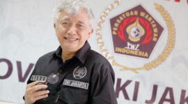 Foto: Dr. Bagus Sudarmanto, S.Sos., M.Si. Seorang pengurus Persatuan Wartawan Indonesia (PWI) DKI Jakarta berpose di sela kegiatan organisasi, dengan latar belakang logo PWI