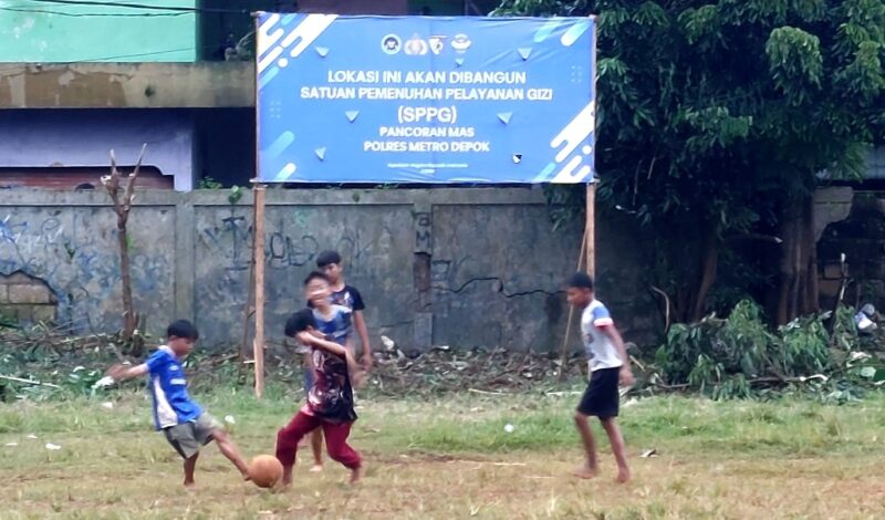 Anak-anak bermain sepakbola di depan Spanduk SPPG Pancoras Mas, yang telah terpasang di Lapangan KONI Depok. (Foto: hw)
