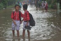 Foto: Murid sekolah dasar melintasi banjir yang merendam kawasan Taman Narogong, Rawalumbu, Bekasi, Jawa Barat, Kamis (22/1/2026). (Dok-Antara)