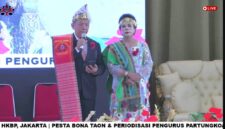 Foto: Ketua Umum terpilih Partungkoan Guru Hinombingan Silitonga se-Jabodetabek periode 2026–2030, Dr. Dikson Silitonga, menyampaikan sambutan didampingi seorang tokoh perempuan dalam balutan busana adat Batak pada acara Pesta Bona Taon dan Periodeisasi Pengurus di Sopo Marpingkir.