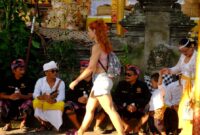 Wisatawan asing melewati masyarakat yang sedang istirahat saat upacara Odalan di Ubud, Bali. (Foto: hw)