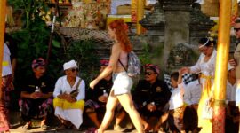 Wisatawan asing melewati masyarakat yang sedang istirahat saat upacara Odalan di Ubud, Bali. (Foto: hw)
