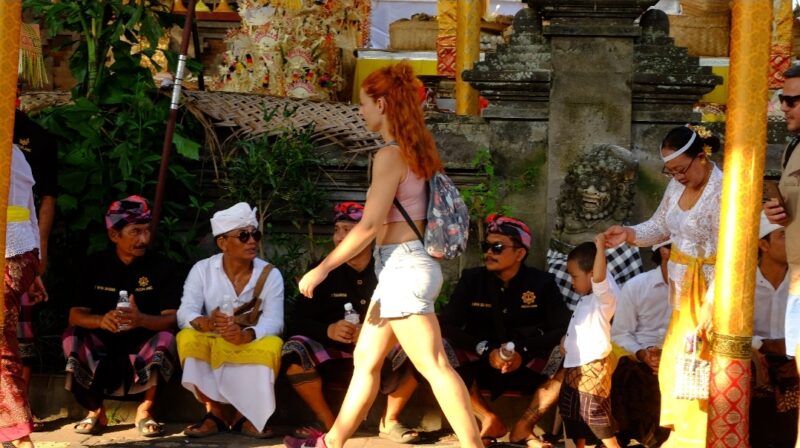 Wisatawan asing melewati masyarakat yang sedang istirahat saat upacara Odalan di Ubud, Bali. (Foto: hw)