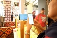 Seorang pembeli di salah gerai di Stasiun LRT Dukuh Atas, membayar menggunakan QRIS melalui aplikasi di telepon genggamnya. (Foto: hw)