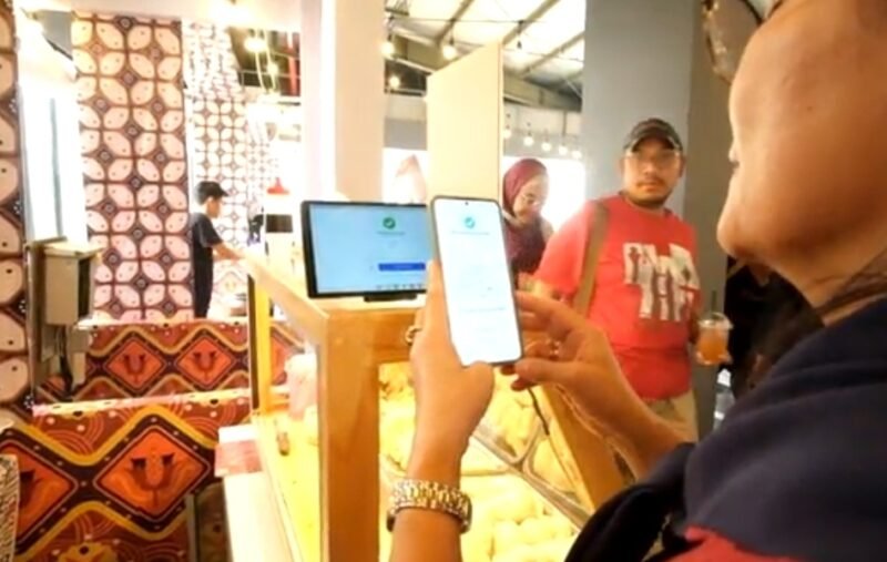 Seorang pembeli di salah gerai di Stasiun LRT Dukuh Atas, membayar menggunakan QRIS melalui aplikasi di telepon genggamnya. (Foto: hw)