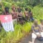 Foto: Sejumlah pria bersenjata berdiri di tepi Jalan Trans Papua, Distrik Seradala, Kabupaten Yahukimo, Papua Pegunungan, sementara dua warga sipil dengan wajah disamarkan terlihat duduk di depan mereka. 