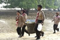 Foto: Anggota Saka Bahari bersama prajurit TNI Angkatan Laut membawa hasil pengumpulan sampah saat mengikuti aksi bersih pantai di kawasan Lapangan Tembak Cakra Kodaeral IV, Batam.