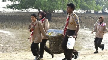 Foto: Anggota Saka Bahari bersama prajurit TNI Angkatan Laut membawa hasil pengumpulan sampah saat mengikuti aksi bersih pantai di kawasan Lapangan Tembak Cakra Kodaeral IV, Batam.