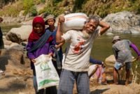 Foto: Seorang warga lanjut usia mengangkut karung berisi material bersama warga lainnya saat bergotong royong mendukung pembangunan Jembatan Garuda di Dusun Mojo, Desa Pucangombo, Kecamatan Tegalombo, Kabupaten Pacitan, Kamis (30/7/2026).
