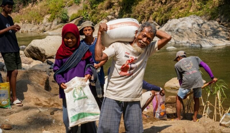 Foto: Seorang warga lanjut usia mengangkut karung berisi material bersama warga lainnya saat bergotong royong mendukung pembangunan Jembatan Garuda di Dusun Mojo, Desa Pucangombo, Kecamatan Tegalombo, Kabupaten Pacitan, Kamis (30/7/2026).