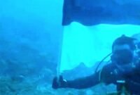 Foto: Romo Kolonel (Purn.) Sus. Yoseph Maria Marcelinus Bintoro, Pr., mengibarkan Bendera Merah Putih di bawah laut perairan Pulau Mimita, seberang Pulau Morotai, Maluku Utara, Senin (17/8/2026).