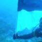 Foto: Romo Kolonel (Purn.) Sus. Yoseph Maria Marcelinus Bintoro, Pr., mengibarkan Bendera Merah Putih di bawah laut perairan Pulau Mimita, seberang Pulau Morotai, Maluku Utara, Senin (17/8/2026).