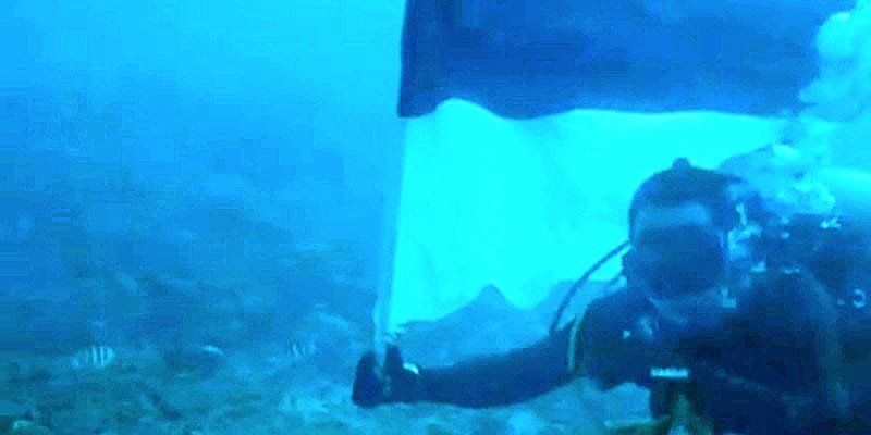 Foto: Romo Kolonel (Purn.) Sus. Yoseph Maria Marcelinus Bintoro, Pr., mengibarkan Bendera Merah Putih di bawah laut perairan Pulau Mimita, seberang Pulau Morotai, Maluku Utara, Senin (17/8/2026).